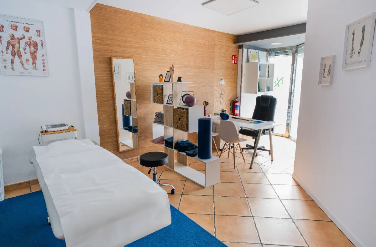 Treatment room with a table and the reception area at Esnatu in Barakaldo
